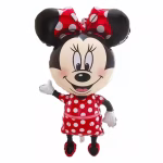 Balon din folie metalizată decupat pe conturul personajului Minnie Mouse, zâmbind larg și salutând cu o mână, purtând clasica rochie roșie cu buline albe, fundă asortată pe cap și pantofi roșii