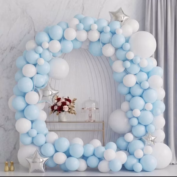 Arcada din baloane asamblata in culori pastelate bleu macarons si alb decorata cu stele din folie argintie prezentata intr un decor rafinat