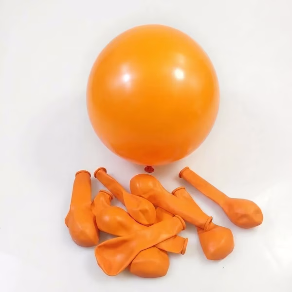 Un balon rotund din latex umflat, având o nuanță intensă de portocaliu, așezat central deasupra unui grup de baloane portocalii pliate și neumflate, pe un fundal alb neutru