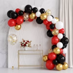 Arcada din baloane asamblata in culorile rosu negru alb si auriu chrome prezentata intr un decor elegant de petrecere