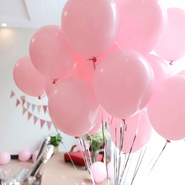 Un buchet elegant de baloane din latex umflate cu heliu, prezentând o nuanță delicată de roz pastel opac, specifică stilului macarons, ancorate grațios cu panglici argintii