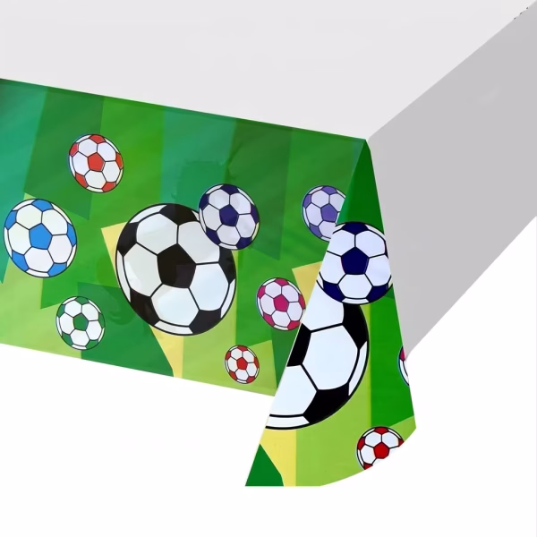 fata de masa fotbal 108x180 cm Detaliu colț masa acoperita cu fata de masa din plastic, evidentiind imprimeul de pe margine cu mingi de fotbal pe fundal verde gazon.
