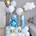 Aranjament din baloane pentru prima aniversare format dintr o baza de latex alb si bleu decorata cu stele aurii o cifra cu coronita un ursulet bleu si un norisor plutitor