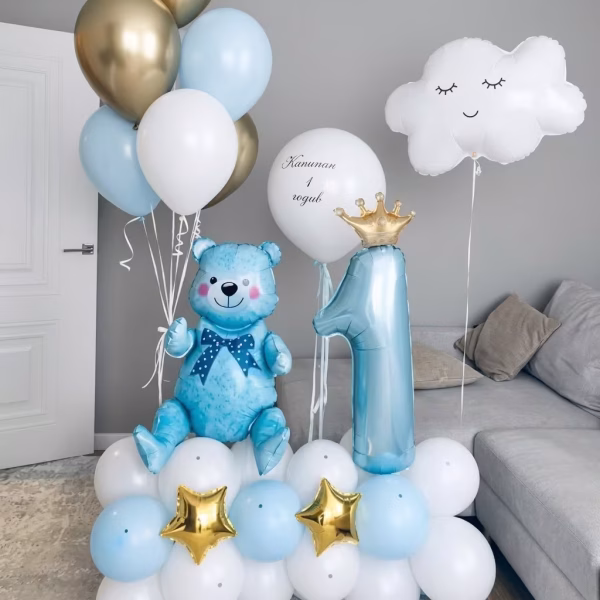 Aranjament din baloane pentru prima aniversare format dintr o baza de latex alb si bleu decorata cu stele aurii o cifra cu coronita un ursulet bleu si un norisor plutitor