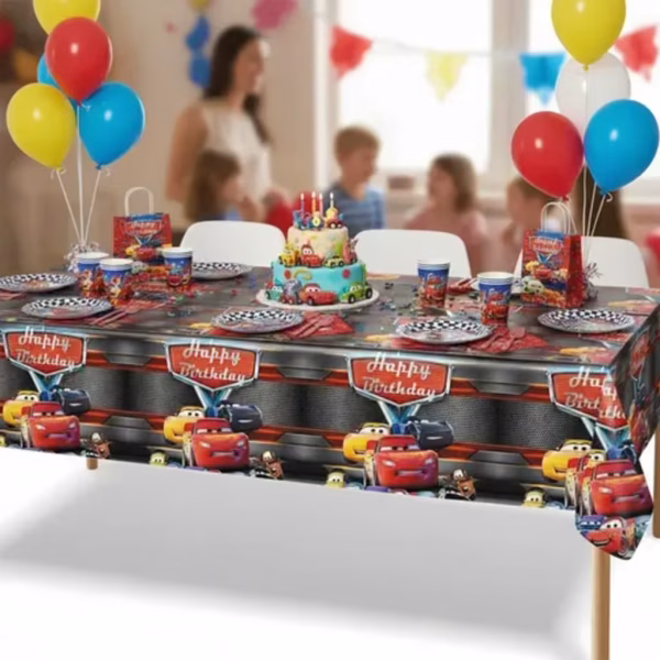 Fata de masa din plastic cu imprimeu tematic masina cars si mesajul Happy Birthday asezata pe o masa festiva decorata pentru copii