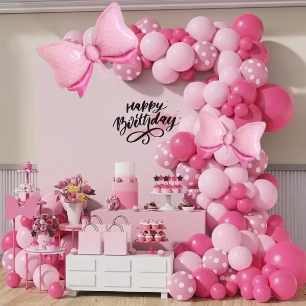 Arcada din baloane asamblata in culori de roz pastel macarons roz inchis prafuit si roz cu buline albe decorata cu balon folie in forma de fundita