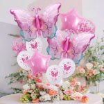 Set de 10 baloane cu tematica fluturi roz din folie si latex asezate intr un buchet festiv deasupra unei mese decorate