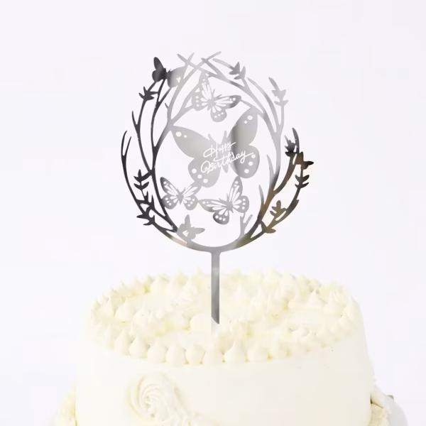 topper tort happy birthday argintiu Topper decorativ pentru tort, mesaj Happy Birthday, culoare argintiu oglindat, material plexiglass premium. Design elegant ce ilustreaza o coronita din ramuri delicate si fluturi.