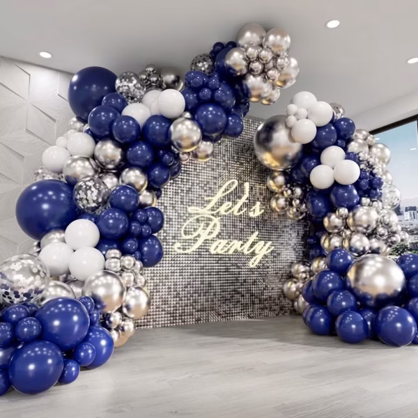 Arcada din baloane asamblata in culori elegante de bleumarin intens alb pur argintiu chrome si baloane transparente cu confetti prezentata in fata unui panou sclipitor