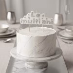 Lumanare cu sclipici argintiu La Multi Ani asezata pe un tort elegant cu aspect de marmura alba si insertii argintii