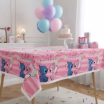 Fata de masa din plastic roz cu personajele Stitch si Angel alaturi de mesajul Happy Birthday asezata pe o masa festiva