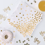 Servetele din hartie alba decorate cu un imprimeu elegant format din buline aurii dispuse sub forma unei cascade de confetti pe diagonala