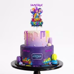 Topper Tort Happy Birthday KPop Demon Hunters Mockup cu topper de tort Happy Birthday K-Pop Demon Hunters așezat pe un tort etajat mov și roz, decorat cu picături colorate și macarons.