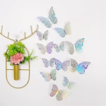 Set 12 Fluturi Decorativi 3D Argintiu Iridiscent – Carton Plastifiat (Model 15) Set 12 fluturi decorativi 3D de culoare argintiu iridiscent holografic, realizati din carton plastifiat premium, cu design decupat tip dantela, pentru aranjamente si torturi.