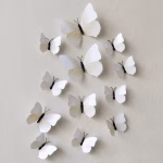 Set 12 fluturi decorativi 3D albi Set 12 fluturi decorativi 3D albi aplicati pe un perete deschis in living