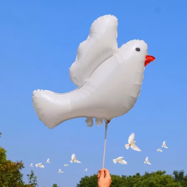 Balon Folie Porumbel Alb, Decor Nunta si Botez Balon din folie in forma de porumbel alb tinut pe un bat, cu un cer senin de vara in fundal.
