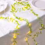 Ghirlanda Frunze Verzi Premium cu Led 300 cm Ghirlanda frunze verzi premium cu LED 300 cm asezata pe o masa festiva.
