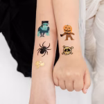 Bratele mai multor copii costumati de Halloween avand aplicate tatuaje temporare cu dovleci, paianjeni, cranii si monstri.