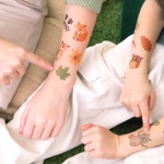 Bratele unor copii avand aplicate tatuaje temporare cu tematica padure, ilustrand o vulpe, o frunza verde, un ursulet si o bufnita.
