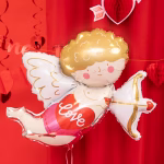 Balon din folie Cupidon umflat cu heliu, plutind deasupra unei mese romantice decorate cu fata de masa rosie, lumanari si un telefon retro.