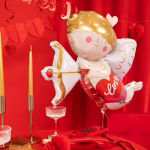 Balon din folie Cupidon umflat cu heliu, plutind deasupra unei mese romantice decorate cu fata de masa rosie, lumanari si un telefon retro.