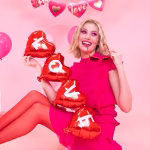 ghirlanda baloane inima love O tanara blonda imbracata in roz, tinand in maini o ghirlanda din baloane folie rosii sub forma de inimi pe care scrie cuvantul LOVE.
