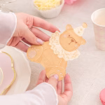 O persoana tinand in mana un servetel in forma de ursulet, deasupra unei mese festive, evidentiind dimensiunea reala si calitatea premium a hartiei.