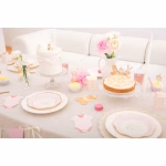 Decor pentru masa de petrecere a unei fetite (botez sau 1 an), evidentiind servetelele in forma de body roz pastel, alaturate veselei elegante, florilor si baloanelor asortate.
