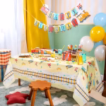 Vedere de sus a unei mese de Candy Bar cu fata de masa Happy Express, plina cu briose dulci, gustari sarate si elemente de vesela in forma de tren.