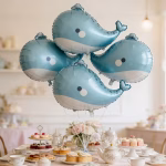 balon folie balena 71 cm Buchet festiv alcatuit din patru baloane in forma de balena plutind cu heliu deasupra unei mese elegante de Candy Bar decorata cu prajituri si ceai.