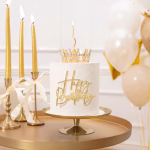 Topper Tort Coroniță Aurie cu Cristale Argintii 10cm Tort alb elegant așezat pe un suport auriu, decorat cu topperul coroniță aurie cu cristale argintii, o lumânare spiralată și un mesaj frontal Happy Birthday auriu, înconjurat de lumânări și baloane.
