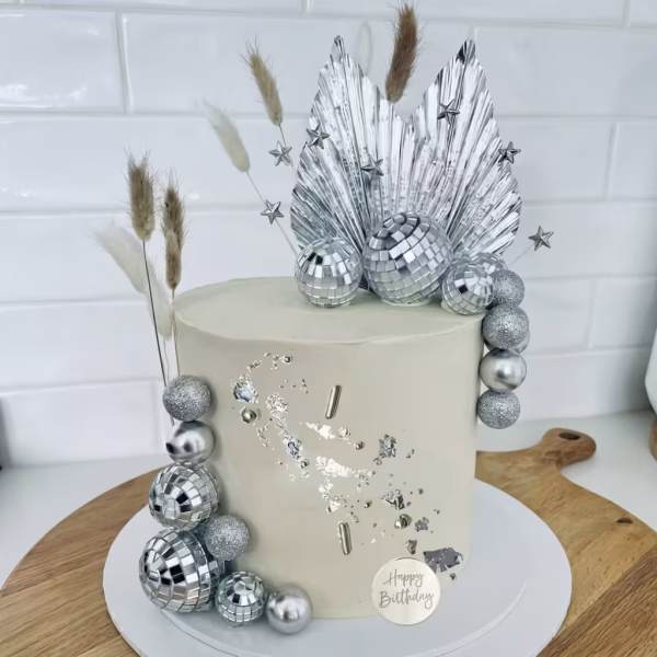 Set 19 Toppere Tort Bile Disco si Argintiu Tort bej elegant, decorat cu accente de foiță argintie, o cascadă de bile disco și argintii, completat în vârf de frunze evantai holografice.