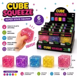 Stand de prezentare plin cu jucarii tip cub antistres in culori variate, cu sclipici, alaturi de o mana care strange un cub roz.