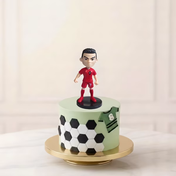 Topper tort figurină 3D Cristiano Ronaldo în echipament roșu de joc, prezentat pe un tort tematic sportiv.
