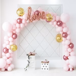 Kit Arcada Baloane Roz Si Rose Gold Cu Suport Arcada din baloane roz pastel rose gold cromate si aurii cu confetti avand un balon din folie in forma de text love in centrul aranjamentului.