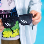 Ochelari de Petrecere Minecraft Un copil ține în mână o pereche de ochelari de petrecere negri cu design pixelat, specific jocurilor video retro de tip 8-bit.