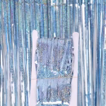 Perdea decorativa tip tinsel in nuanta bleu cu sclipici ambalata pe un suport de carton alb avand in fundal perdeaua desfacuta.