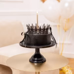 Topper Tort Coroniță Argintie cu Cristale Negre 15cm Tort elegant negru, așezat pe un suport negru, decorat în partea superioară cu o coroniță argintie mare de 15 cm încrustată cu cristale negre și o lumânare înaltă.