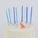 Set 12 Lumanari Tort Bleu Cu Glitter Lumanari subtiri de tort in nuante pastelate de alb si bleu cu glitter asezate elegant pe un tort alb decorat festiv.
