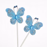 Set de 2 toppere decorative pentru tort, sub formă de fluturi bleu cu aripi din material fin, detalii argintii, mărgeluțe și sclipici, montați pe bețișoare de susținere.