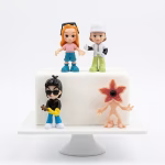 Set 4 Figurine Topper Tort Stranger Things plastic Set de 4 figurine 3D din plastic necasant pentru topper tort, inspirate din serialul Stranger Things, așezate pe un tort simplu alb. Figurinele reprezintă personaje iconice și un Demogorgon.