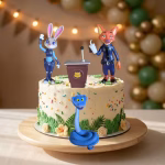 Set 4 Figurine Topper Tort Zootopia Set de 4 figurine 3D din cauciuc siliconic pentru decorarea tortului cu tematica Zootopia, incluzând personajele Judy Hopps și Nick Wilde în uniforme de poliție, un pupitru cu microfon și un șarpe albastru, așezate pe un tort festiv.