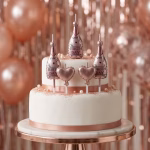 Set 5 Lumanari Tort Sampanie Si Inimi Rose Gold Lumanari de tort in forma de sticle de sampanie si inimi culoarea rose gold asezate pe un tort alb elegant decorat festiv.