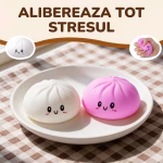Doua jucarii squishy antistres de tip chifla, una alba si una roz, cu fete zambitoare, asezate pe o farfurie pentru a alibera tot stresul.