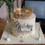 Topper Tort Birthday Princess Acril Argintiu Topper de tort caligrafic cu textul Birthday Princess, realizat din acril argintiu premium cu efect de oglindă, aplicat pe fațada unui tort alb decorat cu o coroană regală aurie, perle și foiță de aur.