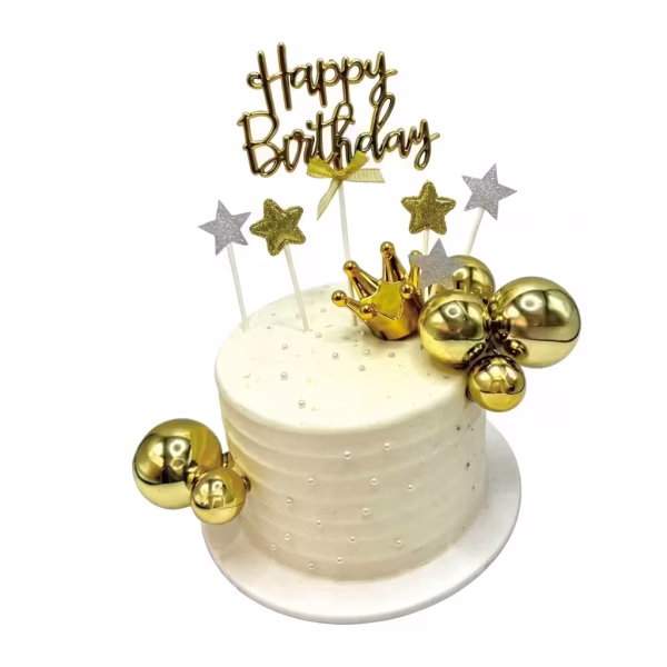 Tort alb decorat cu sfere aurii lucioase de diferite dimensiuni, o coronita aurie tridimensionala, stele cu sclipici si un topper auriu cu mesajul Happy Birthday asezat central