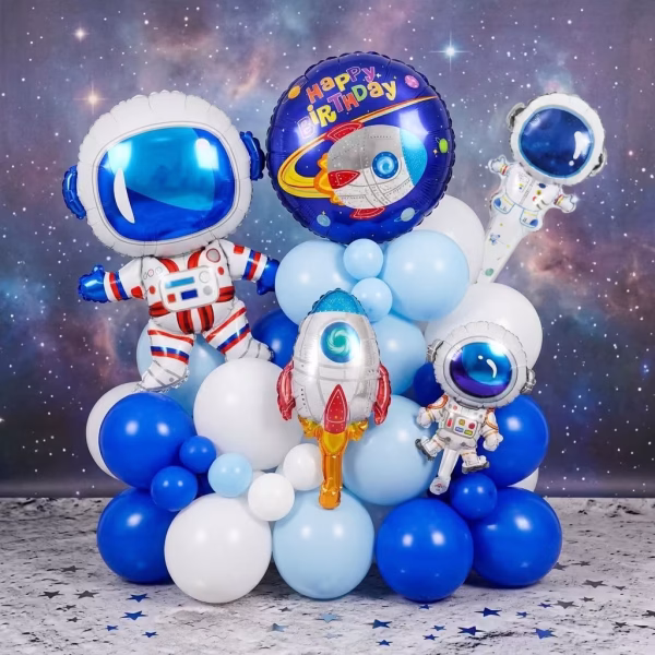Aranjament spectaculos format din 29 de baloane din folie metalizata si latex in nuante de alb si albastru cu figurine astronaut racheta si mesaj aniversar pe un fundal cu constelatii