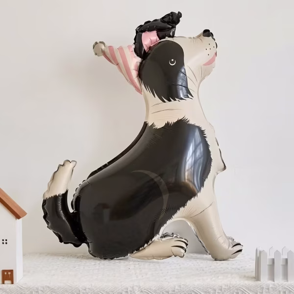 Balon din folie tip airwalker in forma de caine alb cu negru purtand un coif de petrecere roz asezat pe o suprafata alba