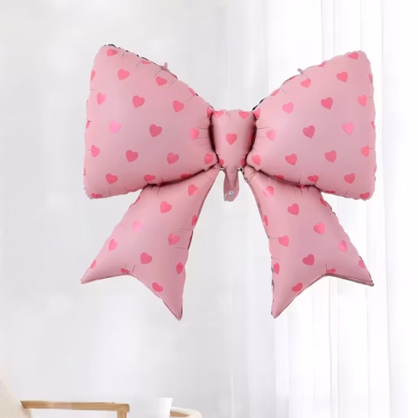 Balon din folie metalizata supradimensionat sub forma de fundita roz decorat cu un imprimeu delicat de inimioare roz inchis