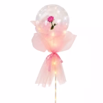 Balon transparent sferic iluminat cu LED uri ce contine un trandafir roz in interior fiind decorat cu tulle si panglica roz pe un suport de expunere